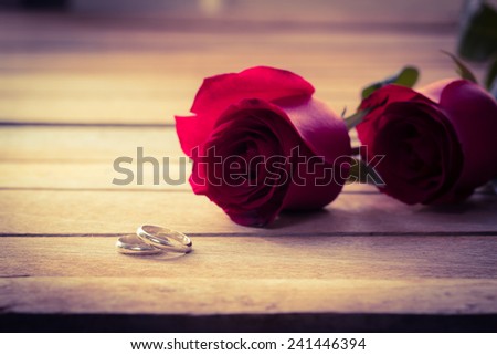 Couple ring with red rose on wood table,Pantone color