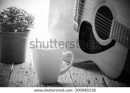 Coffee cup and acoustic guitar next the window with drop water,black and white