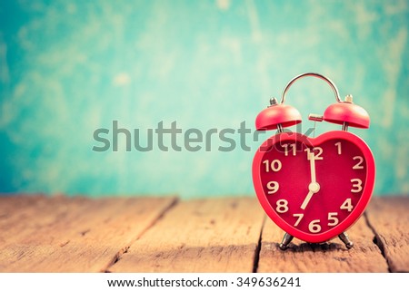 Vintage background with red heart alarm clock on table