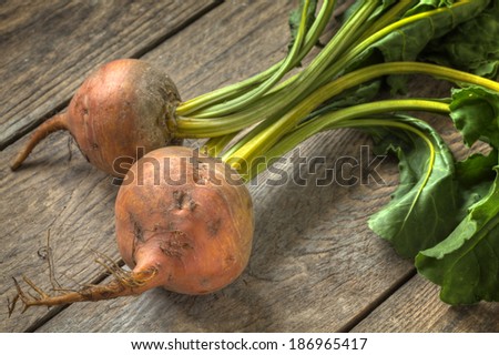 Freshly harvested golden beetroot lying on top of a timber table.