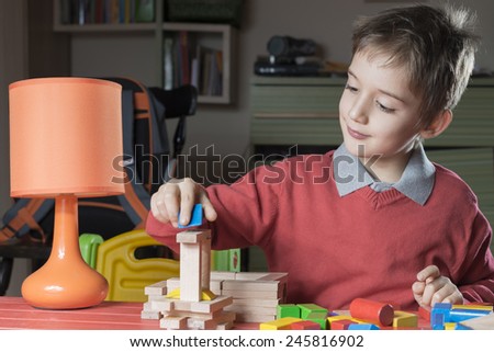 boy is arranging wooden constructor toy parts