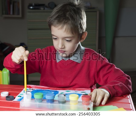 young boy is painting a paint. child painter in a room.