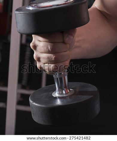 Arm attractive athletic man holds heavy dumbbell. shot in in gym. fitness theme.