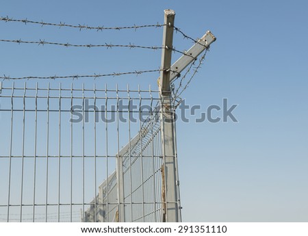 Metal fence. Metal grid fence with barbed wire at the top.