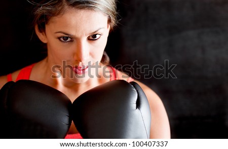 Athletic woman boxing with black gloves