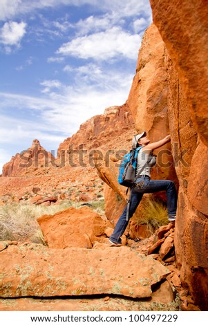 Female explorer at the desert climbing a rocky mountain