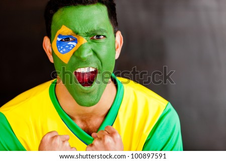 Brazilian man shouting with the flag painted on his face