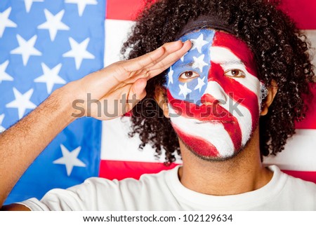 Patriotic American man with the USA flag painted on his face saluting