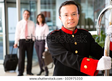 Hotel bellboy carrying the luggage of  a business couple