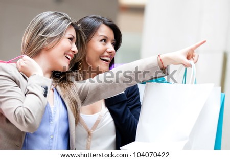 Shopping women pointing at a window and smiling