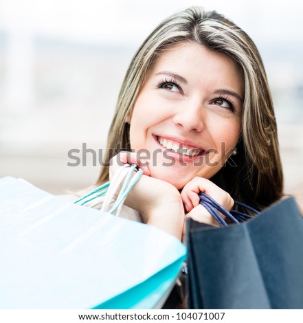 Pensive female shopper holding bags and looking up