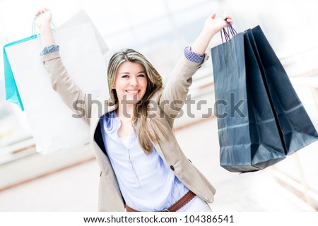 Happy shopping girl with arms up holding bags