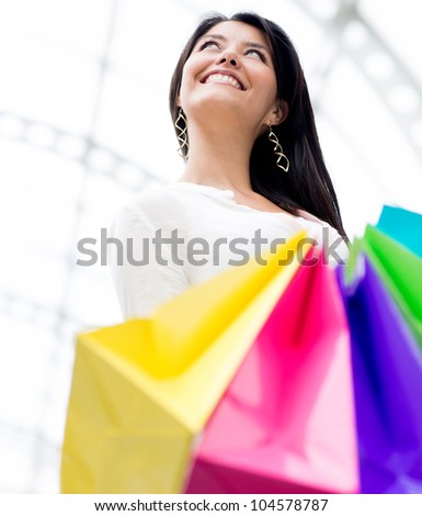 Female shopper holding colorful shopping bags and smiling