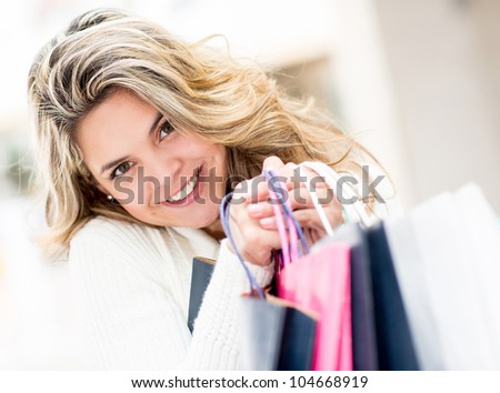 Cute female shopper holding shopping bags and smiling