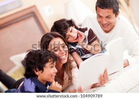 Happy family reading a book in bed