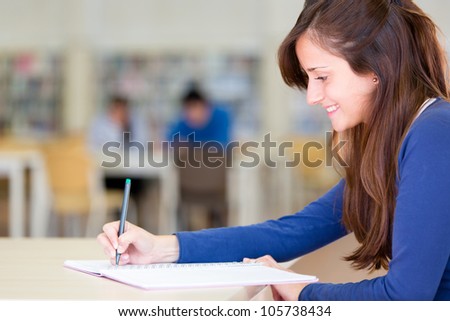 Happy young woman studying at the library
