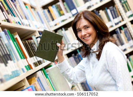 Librarian placing a book in the bookshelf and smiling