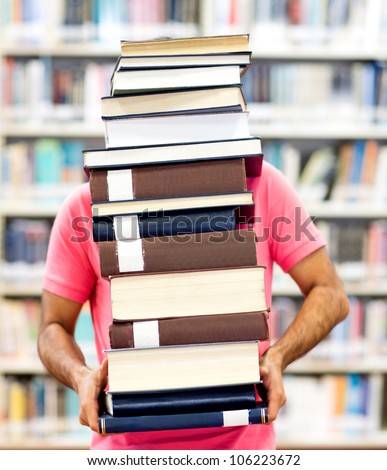 Male student carrying heavy books at the library