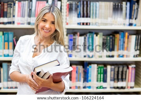 Happy female student carrying books at the library