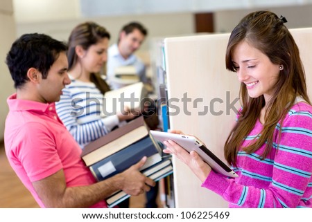 Woman with tablet computer reading an e-book and friends carrying heavy books