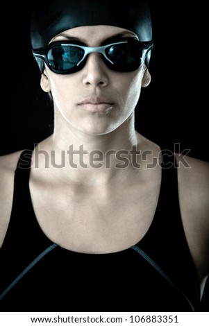 Professional female swimmer with goggles and a hat - isolated over a black background