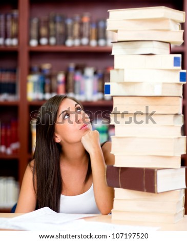 Busy female student with a pile of books at the library