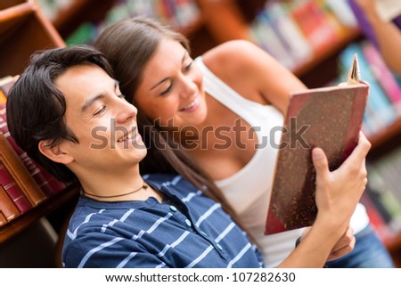 Couple of students at the library reading a book