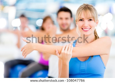 Group Of People Exercising At The Gym And Stretching