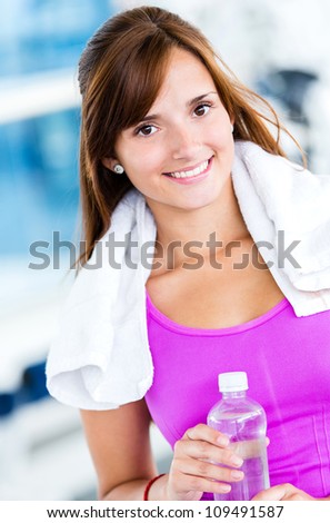 Happy woman at the gym holding a bottle of water