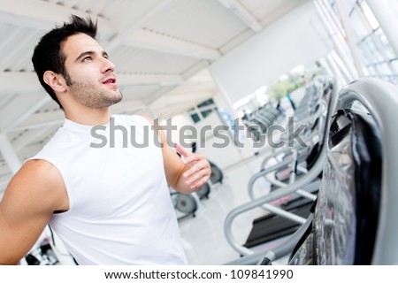 Handsome gym man running on the treadmill