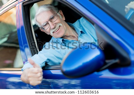 Happy male driver with thumbs up in a car