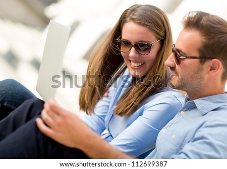 Happy couple on holidays staying in touch through a laptop