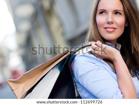 Female shopper daydreaming and holding shopping bags