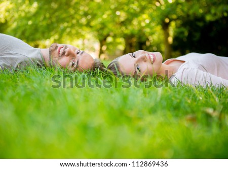 Young loving couple lying at the park  with heads together