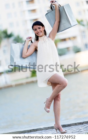 Happy shopping woman  with arms up holding bags