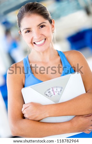 Happy gym woman holding weight scale