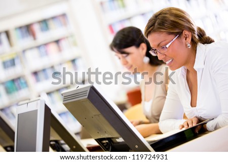 Female students researching at the library on computers