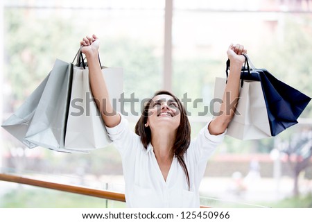 Happy shopping woman with arms up holding bags