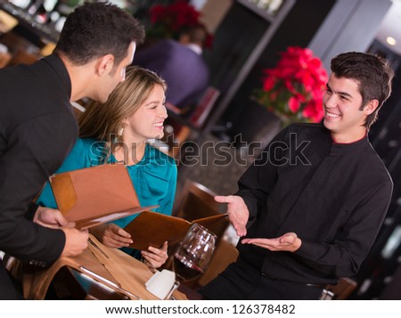 Waiter explaining the menu to a couple at the restaurant
