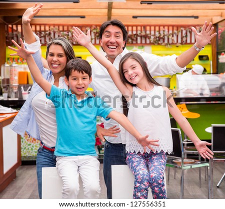 Excited family with arms up at a restaurant