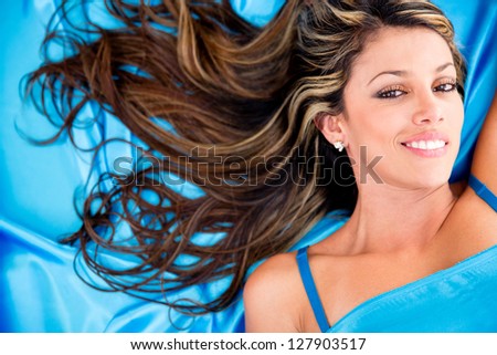 Beautiful aqua woman in a dress lying on blue fabric