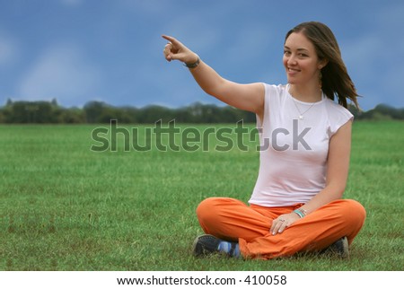 beautiful girl sitting on a park pointing.  Good a web menu or a button on the tip of her finger