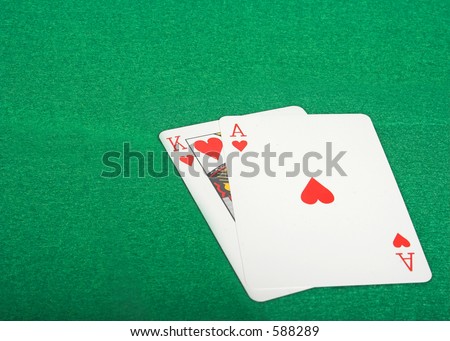 ace and king of hearts over a green felt