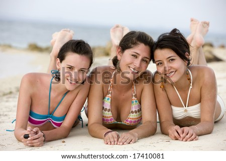 stock photo Teenage girls at the beach smiling while lying on the floor