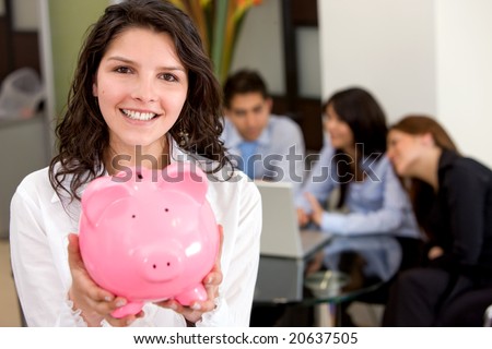 business woman showing her savings in a piggy bank at her office