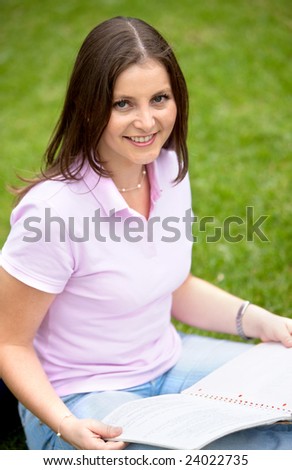 female university student smiling with a notebook outdoors