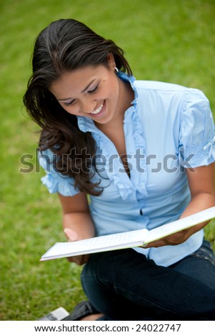 Beautiful woman smiling and studying outside with a notebook
