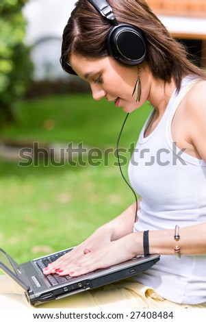 Casual woman listening to music on the computer outdoors