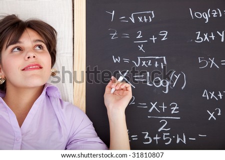 Beautiful girl writing math equations on a chalkboard