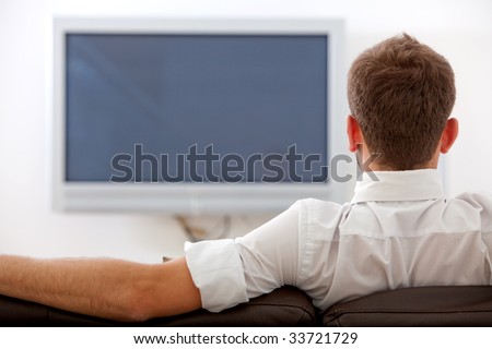 back of man watching tv on a sofa